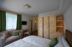 1 dormitorio con cama, sofá y escritorio en Agriturismo Florandonole, en Fai della Paganella