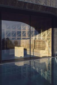 a bench in a building with a reflection in the water at Hotel Milla Montis in Maranza