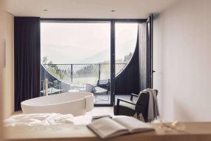 a bedroom with a tub and a balcony with a view at Hotel Milla Montis in Maranza