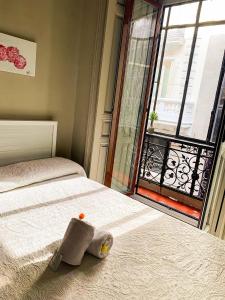 un animal de peluche está sentado en una cama con una ventana en El Hostall, en Madrid