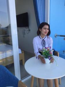 ドンホイにあるTuấn Anh 2 Hotelの花鉢のテーブルに座る女