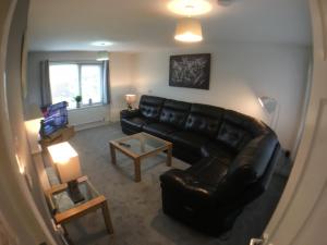 a living room with a black leather couch and a table at 5 bedrooms, 2 Reception Rooms, 2 Shower Rooms, Sleeps up to 7, Parking, Free WiFi & Netflix, Large Garden in Corby