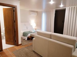 Quinta da Eira do Sol في غيمارايش: غرفة معيشة مع سرير وأريكة