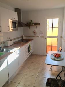 a kitchen with white cabinets and a table with fruit on it at Casa Tortuga in Caleta De Fuste