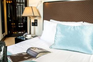 a book on a bed with a pillow and a lamp at Astoria Hotel in Lviv