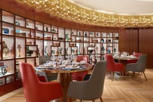 una sala da pranzo con tavoli, sedie e una parete di scaffali di Shangri-La Apartments a Dubai