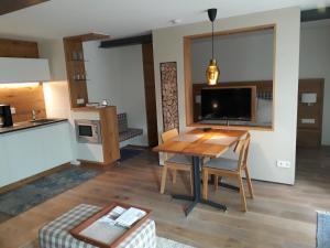 ein Wohnzimmer mit einem Holztisch und einem TV in der Unterkunft Apartment am Kniebach in Immenstaad am Bodensee