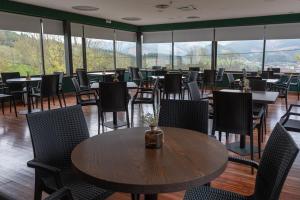 un comedor con mesas, sillas y ventanas en Soraluze Hotela, en Oñate