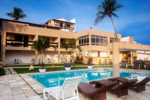 a house with a swimming pool in front of a house at Alimar Hotel in Natal