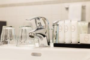 a kitchen counter with a faucet and glasses on a shelf at Prominent Inn Hotel in Noordwijk aan Zee