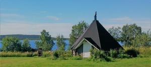 una pequeña capilla en un campo con un lago en Piilijärvi Camping, en Gällivare