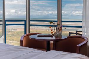 a woman sitting at a table in a hotel room at Prominent Inn Hotel in Noordwijk aan Zee
