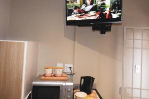 a flat screen tv hanging on a wall above a microwave at Koemi in Kempton Park