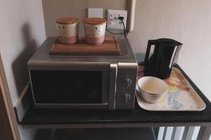 a microwave on a counter with three cups on it at Koemi in Kempton Park