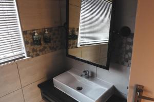 a bathroom with a sink and a mirror at Koemi in Kempton Park +7 photos