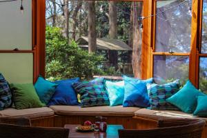 eine Couch mit Kissen vor einem Fenster in der Unterkunft Tomah Retreat - Studio RELAX with fireplace in Mount Tomah