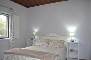 Un dormitorio blanco con una cama y una ventana. en Casa Avô São Miguel, en Angra do Heroísmo