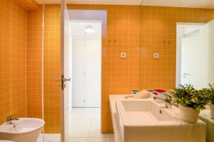 an orange tiled bathroom with a sink and a toilet at Modern Apartment by the Sea in Quarteira +15 photos