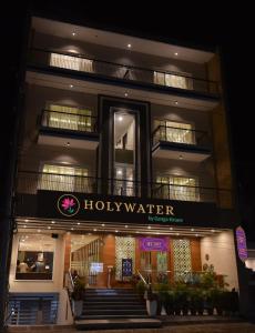 リシケーシュにあるHOLYWATER by Ganga Kinareの聖水看板が貼られたホテルの建物