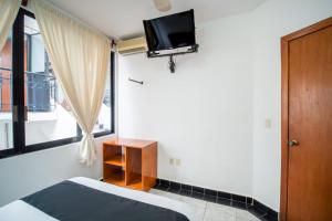 1 dormitorio con 1 cama y TV en la pared en Posada Jois, en Santa Cruz Huatulco