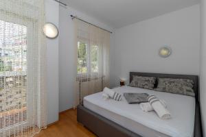 a white bedroom with a bed with towels on it at Apartments Školjka in Rijeka