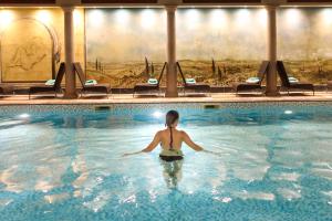 a woman is standing in a swimming pool at Rowhill Grange Hotel & Utopia Spa in Dartford