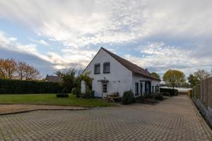 Uma casa branca com uma entrada de tijolos à frente. em Eindeloos Asselt em Swalmen
