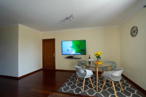 a living room with a table and chairs and a tv at Ocean Breeze in Caniço