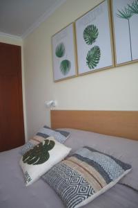 - un lit avec 2 oreillers et 3 photos sur le mur dans l'établissement Ocean Breeze, à Caniço 22 autres photos