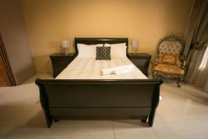 a bedroom with a large bed with a chair at Ein Gedi Premier Weddings And Conferences in Kimberley +15 photos