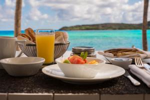 une table avec une assiette de nourriture et un verre de jus d'orange dans l'établissement Le Sereno, à Gustavia