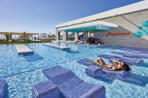 una mujer tendida en una piscina en un resort en Riu Palace Baja California - Adults Only - All Inclusive en Cabo San Lucas
