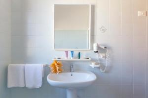 bagno con lavandino, specchio e asciugamani di Residence Smeraldo a San Vito lo Capo
