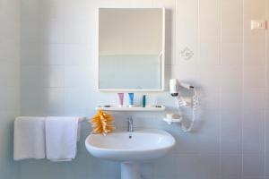 un bagno con lavandino, specchio e asciugamani di Residence Smeraldo a San Vito lo Capo