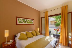 Un dormitorio con una cama con almohadas amarillas y una ventana en Residence Smeraldo en San Vito lo Capo