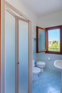 bagno con due servizi igienici, lavandino e finestra di Residence Smeraldo a San Vito lo Capo