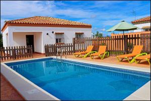 a swimming pool with chairs and a house at Chalet rústico Roche in Conil de la Frontera