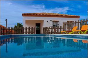 a villa with a swimming pool in front of a house at Chalet rústico Roche in Conil de la Frontera