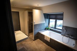 uma casa de banho com uma banheira, um chuveiro e um lavatório. em OP10 Logeren em Oldenzaal