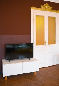 uma televisão sentada num armário branco ao lado de uma porta em Highlight Suite Augarten em Viena