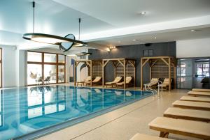 a large swimming pool with chairs and tables in a building at Artus Resort in Karpacz
