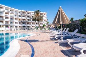 basen z krzesłami i parasolem oraz hotel w obiekcie Apartamento JOSE w mieście San Bartolomé