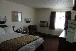 a hotel room with a bed and a chair and a window at Lone Tree Inn in Sidney