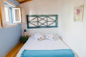 a bedroom with a white bed with two pillows at Quinta das Alfazemas in Ericeira