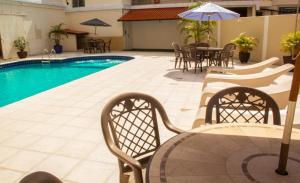 a pool with chairs and tables and an umbrella at Aguas do Iguaçu Hotel Centro in Foz do Iguaçu