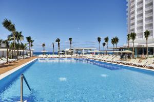 a large swimming pool with lounge chairs and the ocean at Riu Palace Paradise Island - Adults Only - All Inclusive in Nassau