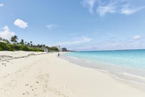 a person walking on a beach near the water at Riu Palace Paradise Island - Adults Only - All Inclusive in Nassau