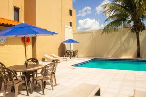 un patio con tavoli, sedie e piscina di Aguas do Iguaçu Hotel Centro a Foz do Iguaçu