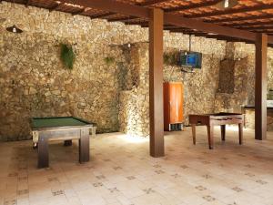 um quarto com duas mesas de pingue-pongue e uma parede de pedra em Casa Angra Itanema em Angra dos Reis