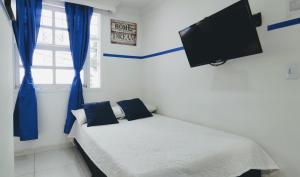 1 dormitorio con 1 cama con cortinas azules y TV de pantalla plana en Casa Hotel Manco Mora, en Medellín